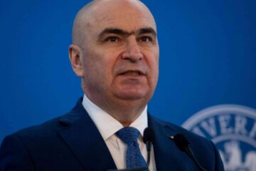 Bolojan se pregătește să dea, pentru a doua oară, foc Constituției. Legea interzicerii cumulului pensiei cu salariul la stat frizează trei decizii anterioare ale CCR